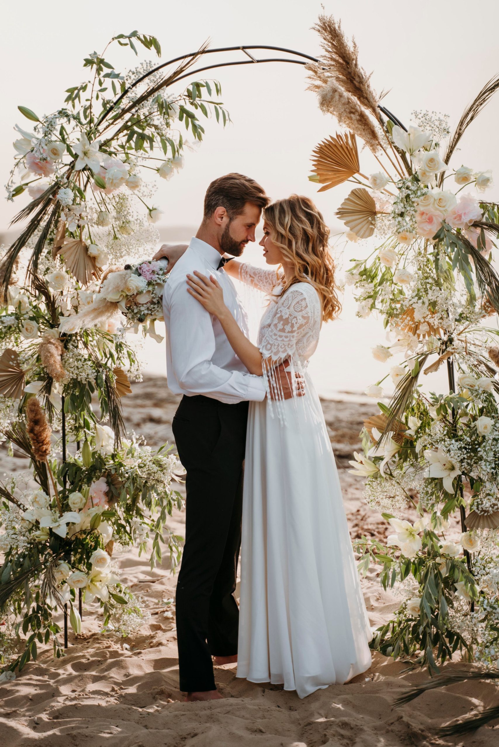 Pareja bajo un arco de flores secas en la playa